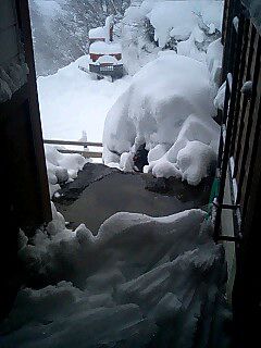 屋根から下ろした雪を温泉で溶かす